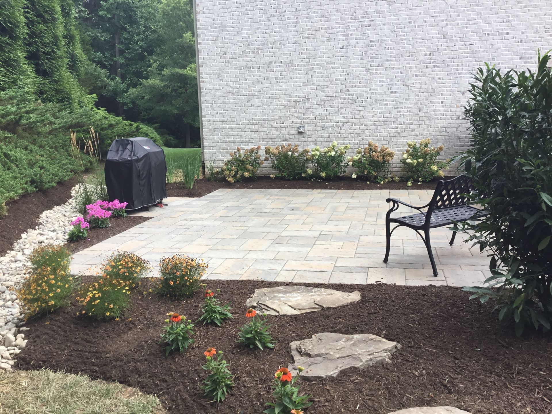 A patio with a bench and a grill in the backyard of a house.