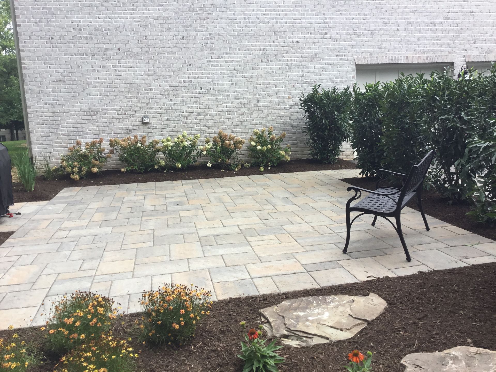 A bench is sitting on a patio in front of a white brick building.