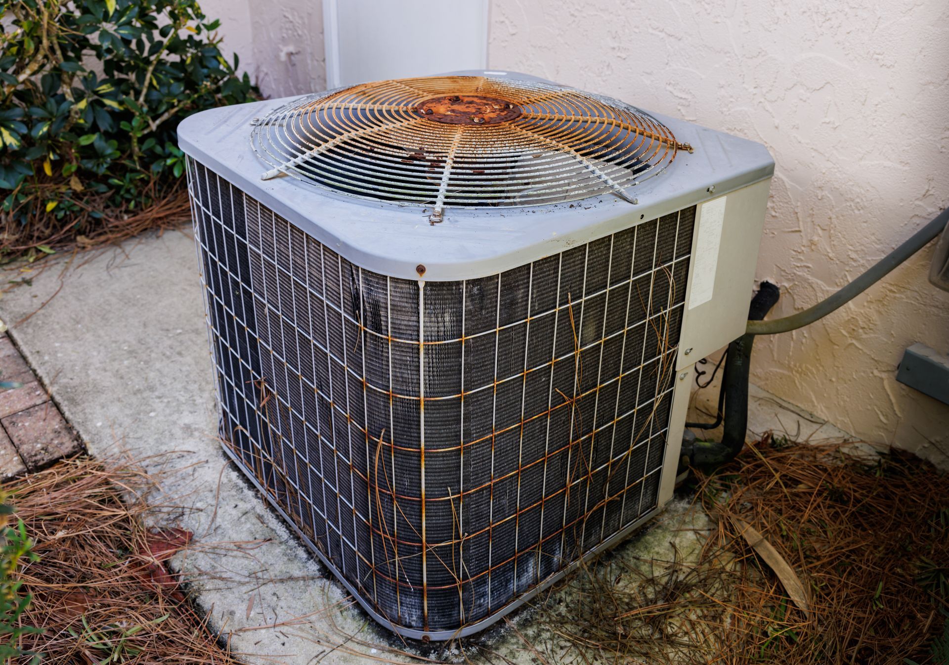 A hand removing a dusty, mesh filter from a white window air conditioning unit.