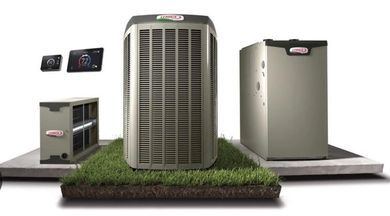 A person sliding a new, clean rectangular air filter into the side slot of a black furnace unit.