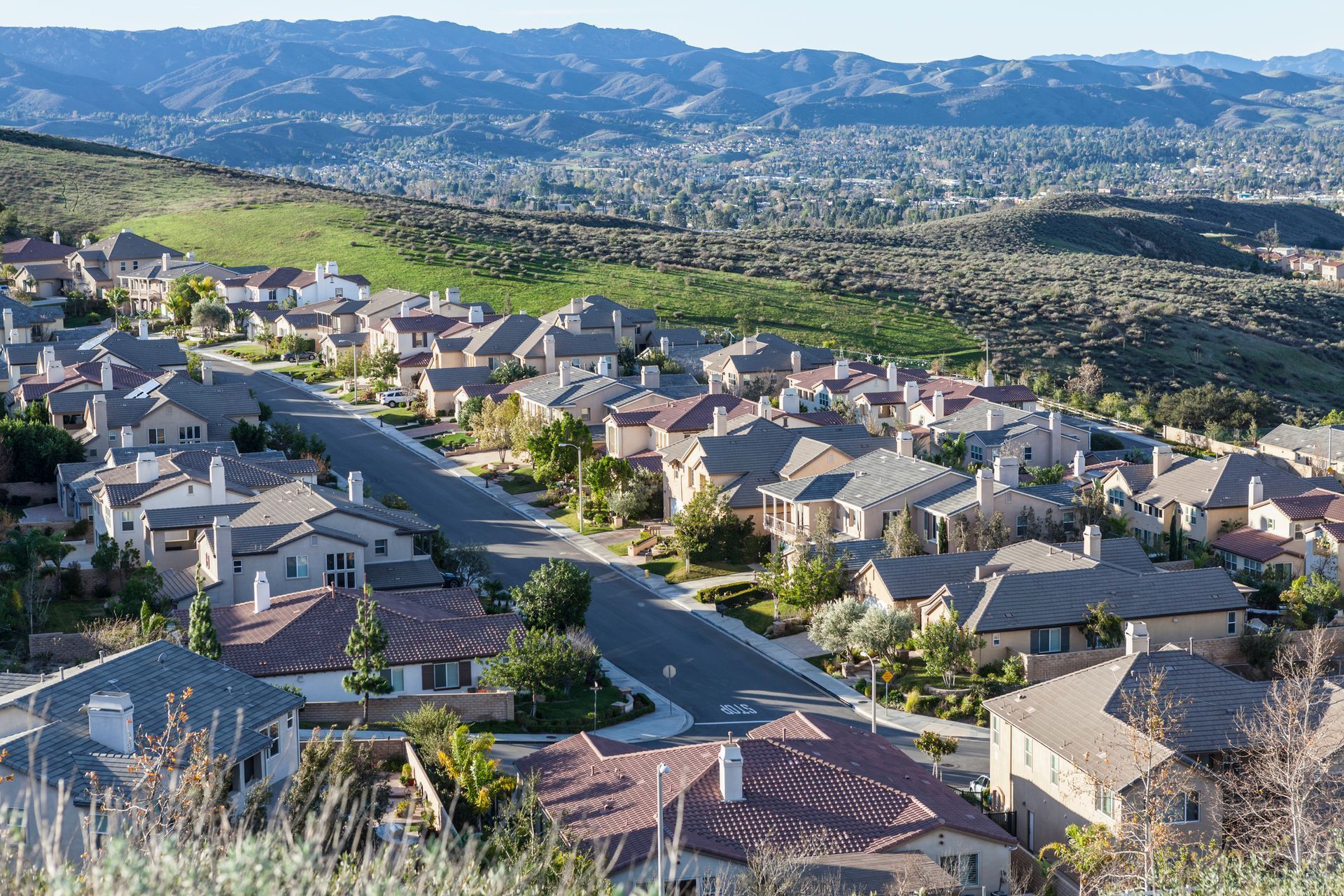 An aerial view of a residential neighborhood with mountains in the background.