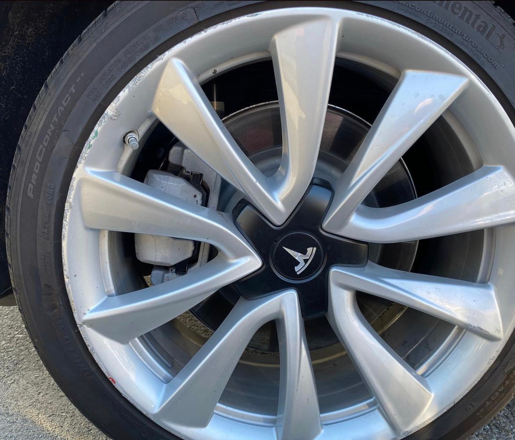 A close up of a tesla wheel with a continental tire