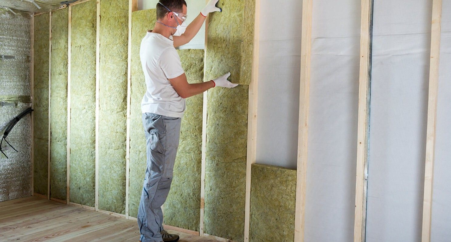 Worker installing thick batt insulation into a wall cavity.
