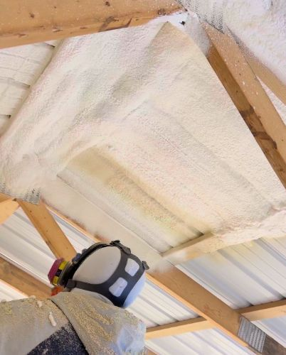 Worker spraying foam insulation on ceiling.