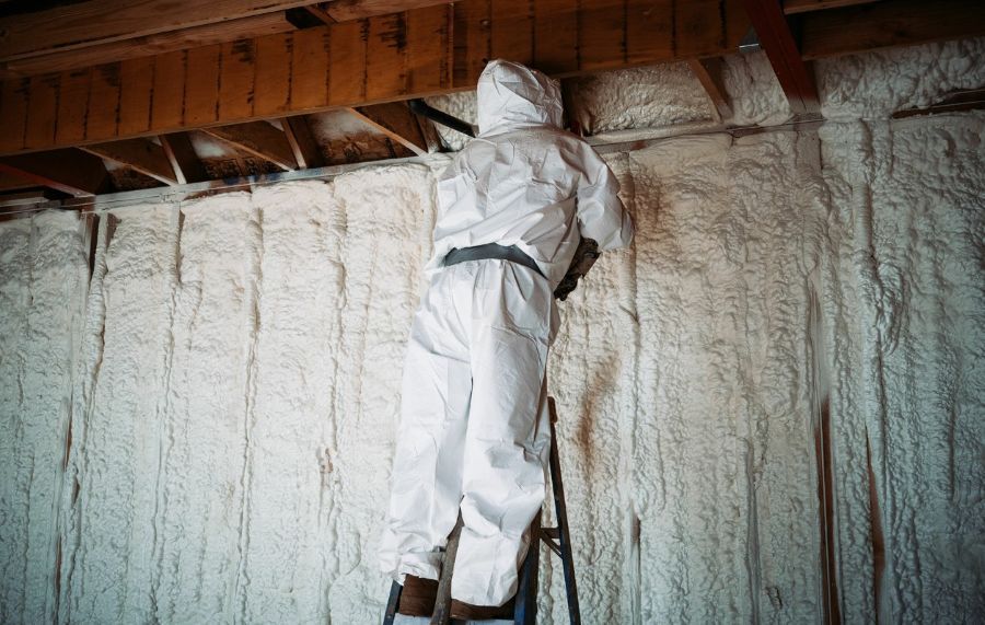 Worker applying spray foam insulation to a residential attic
