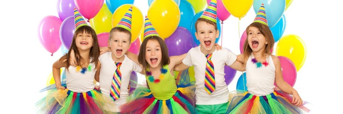 A group of children are standing next to each other in front of balloons at a birthday party.