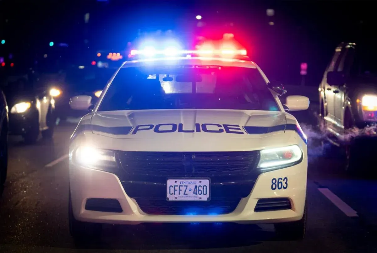A police car is driving down a street at night.