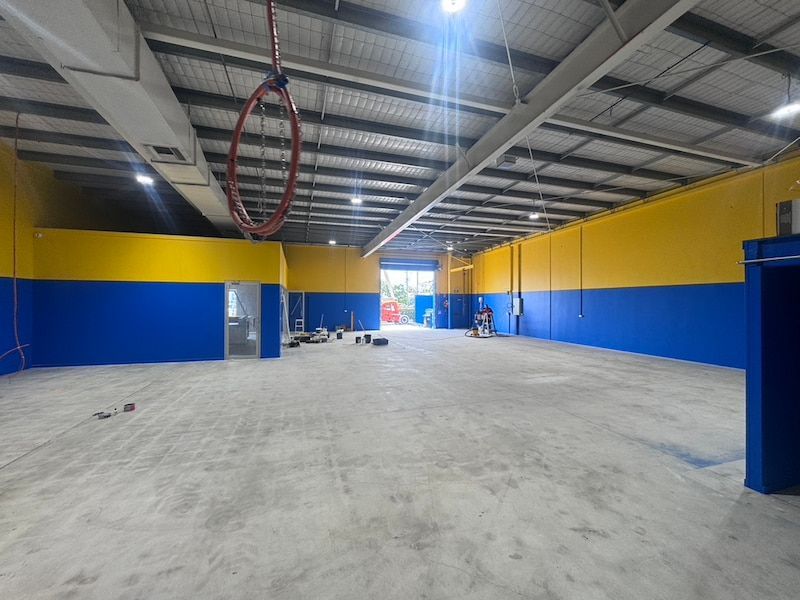 A Large Empty Warehouse With Blue and Yellow Walls — Dezigner Finishes Professional Painting & Decorating in Noosa Heads, QLD