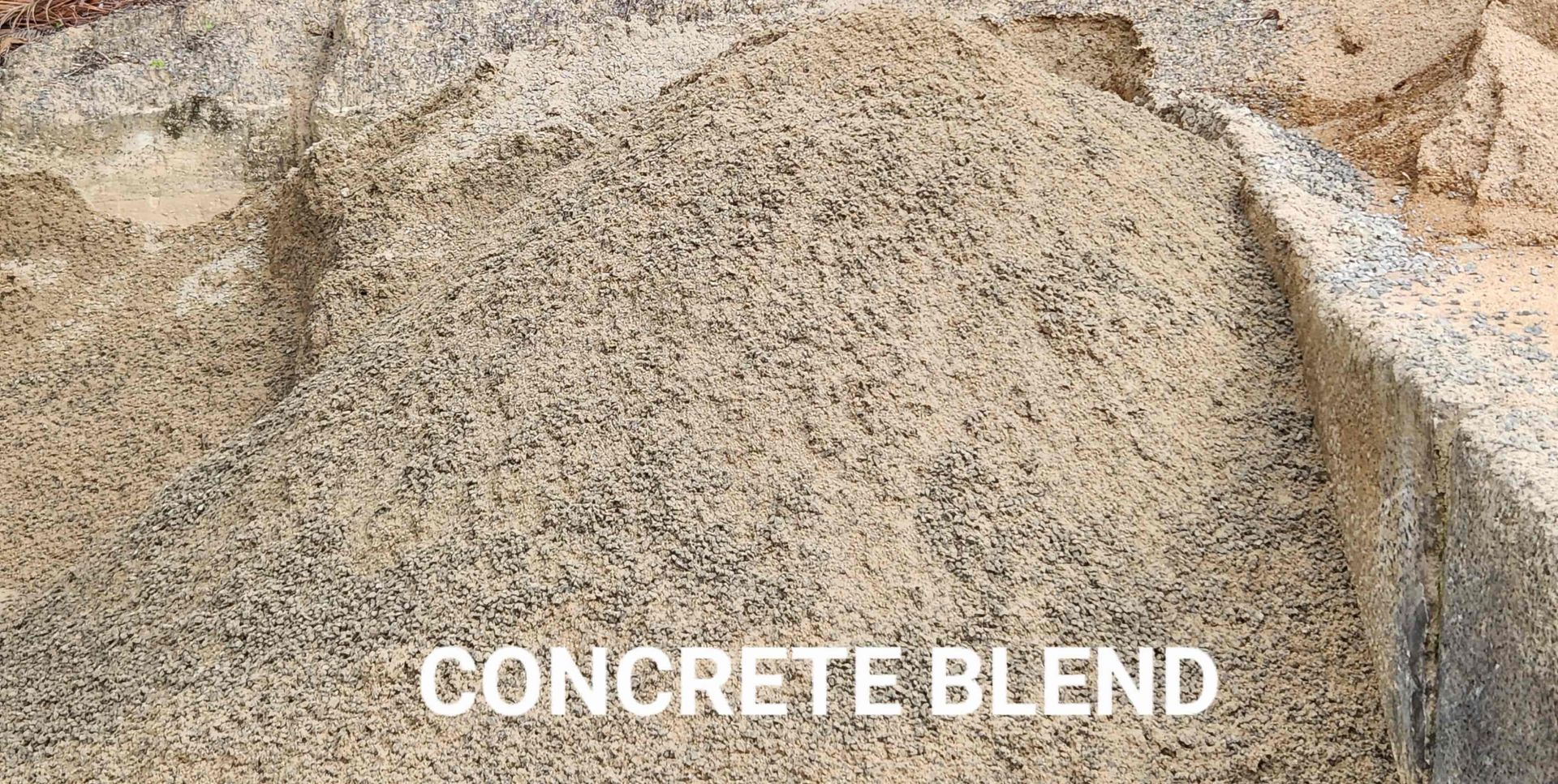 A pile of concrete blend is sitting on top of a pile of sand.