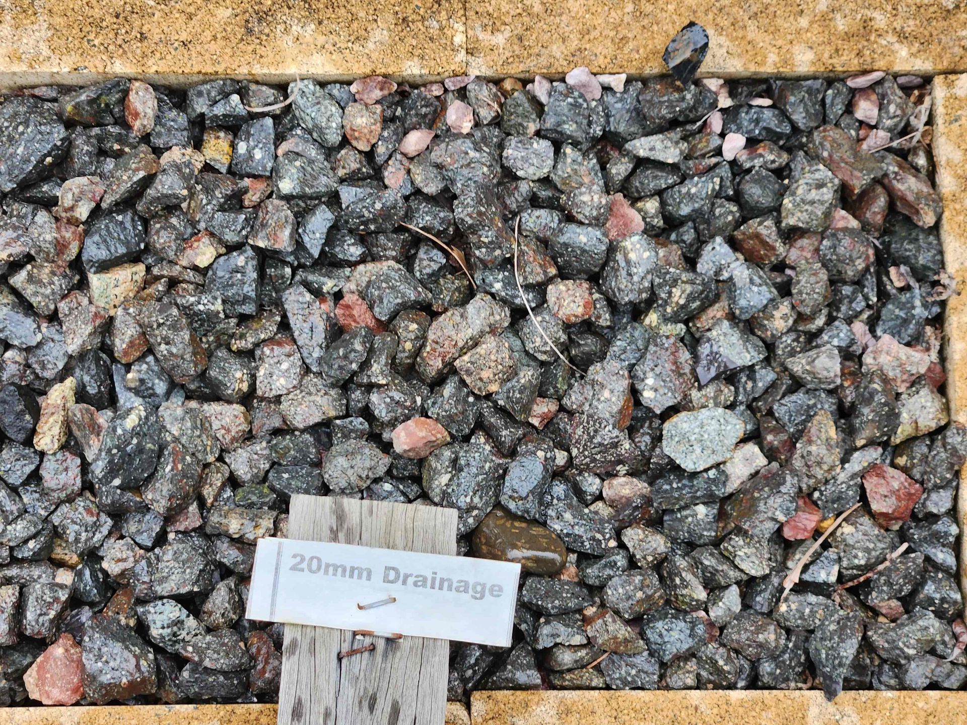 A pile of rocks with a sign that says `` 20mm drainage '' on it. — T&G Sand and Gravel In Sippy Downs, QLD