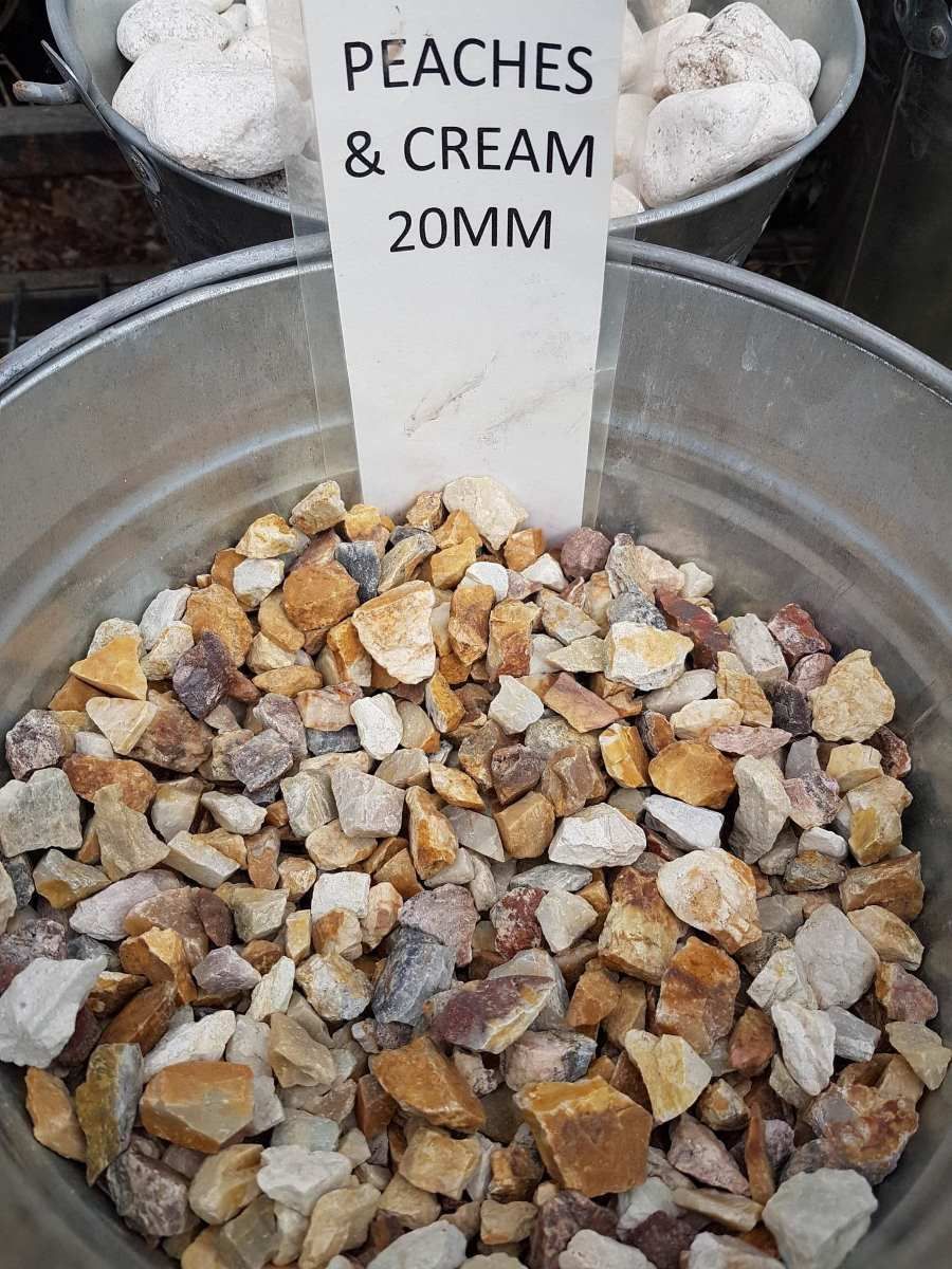 A Metal Bucket Filled With Rocks And A Sign That Says Peaches And Cream 20mm — T&G Sand and Gravel In Sippy Downs, QLD