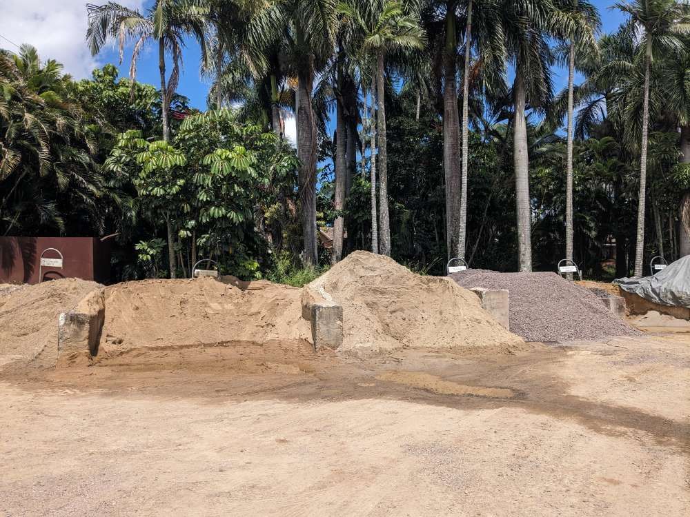 A Pile Of Dirt In A Field With Palm Trees In The Background — T&G Sand and Gravel In Maleny, QLD