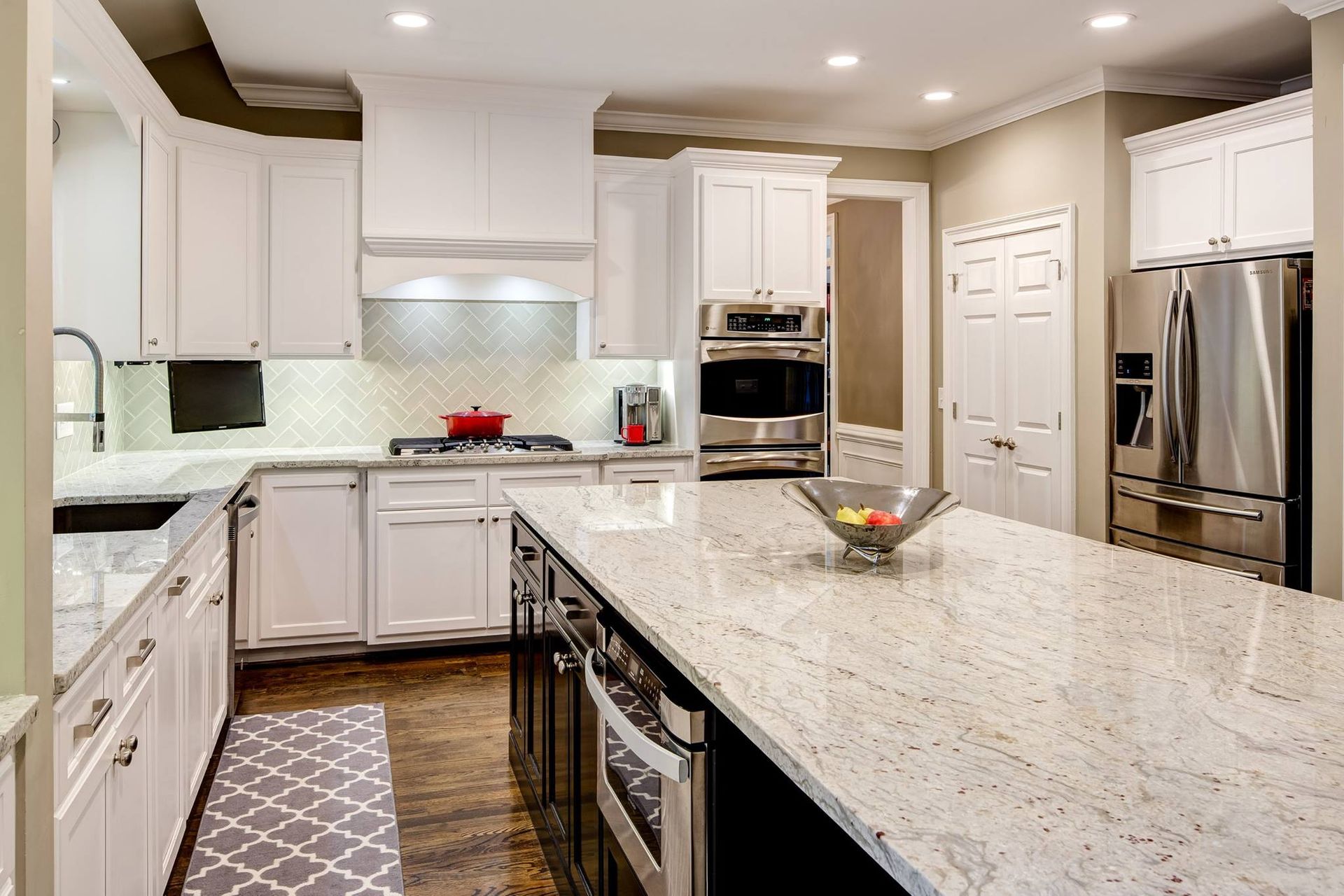 White kitchen with a large island and stainless steel appliances.
