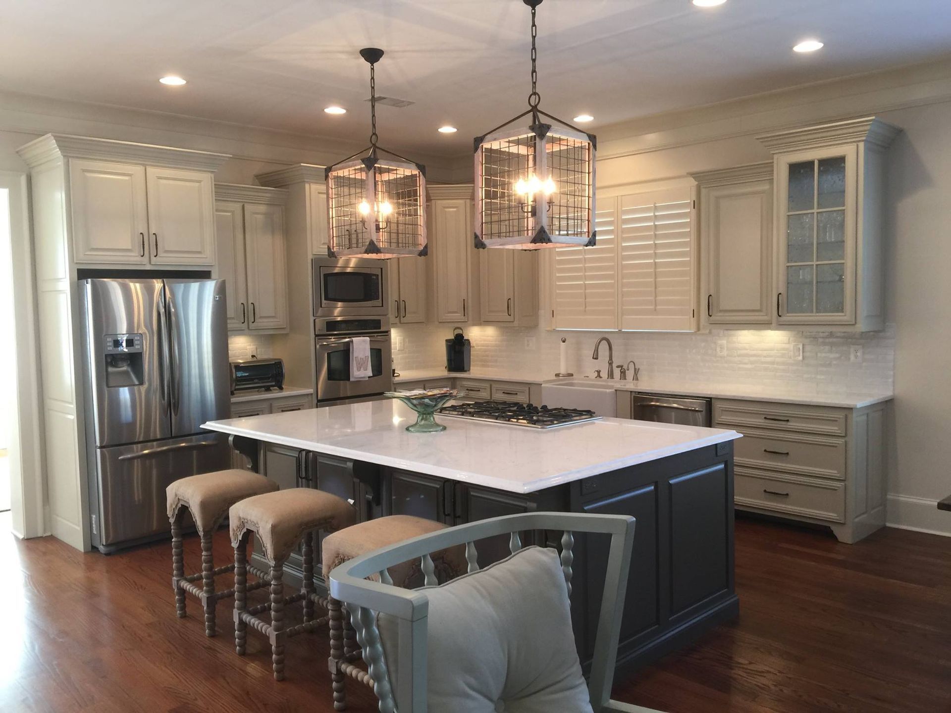 Kitchen with gray cabinets, white countertops, stainless steel appliances, and a large island with seating.