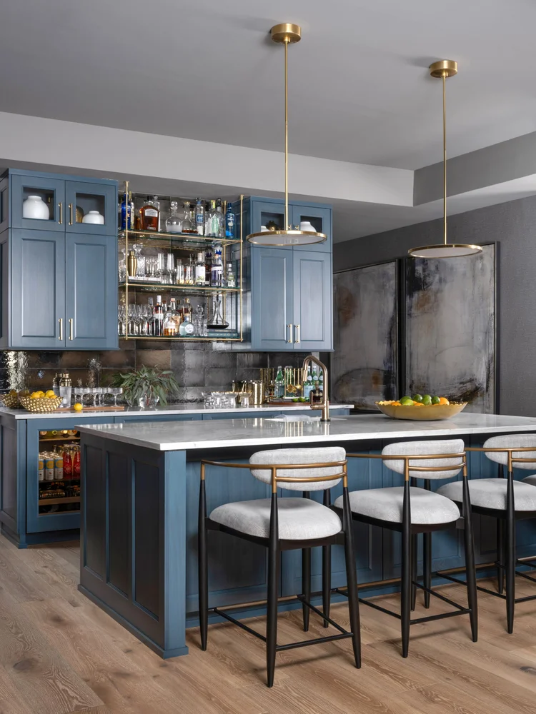 Blue kitchen bar with gold accents, marble countertop, and bar stools.