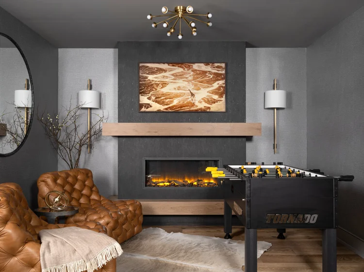 Game room: Tan leather chairs, foosball table, fireplace with art, grey walls, gold accents.