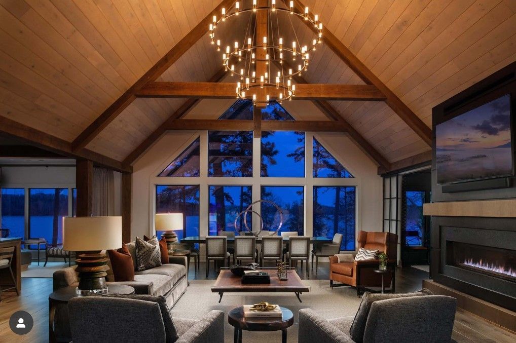 Living room with high wood-beamed ceilings, large windows, and a chandelier.