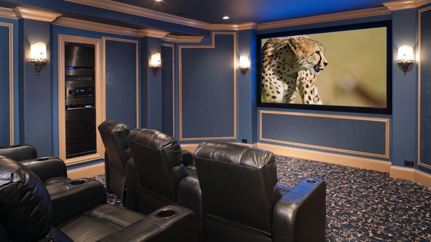 Home theater with blue walls, black leather recliners, and a cheetah on the screen.