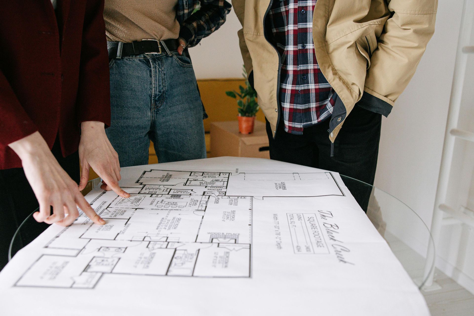 Three people examining a blueprint, pointing, discussing home renovation plans.