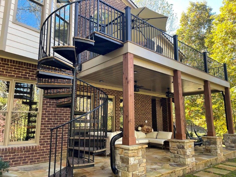 Spiral staircase attached to a two-story deck on a brick building, exterior.