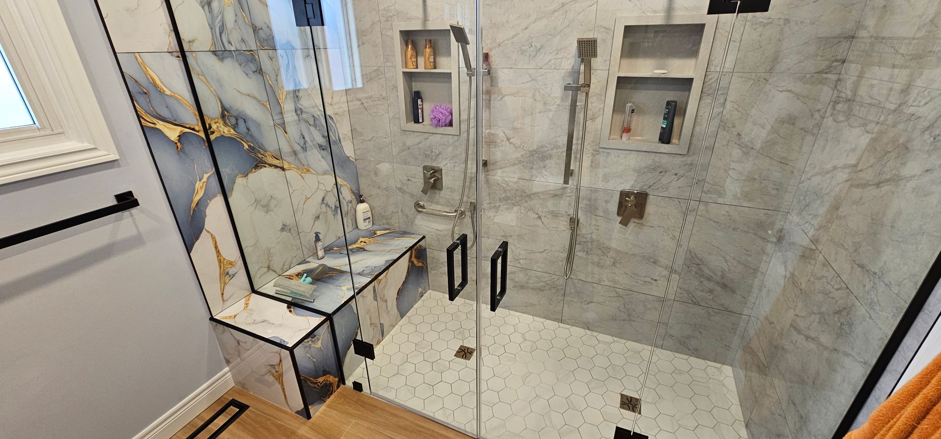 Modern bathroom with a glass shower, marble tile, and black fixtures.