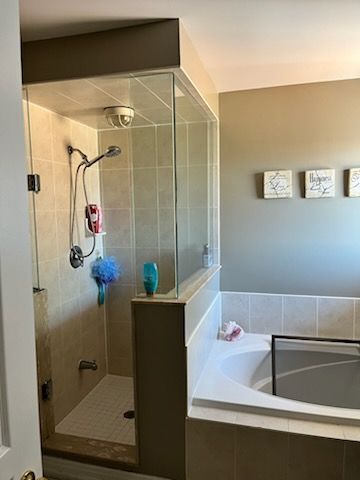 Bathroom with a glass-enclosed shower, beige tile, and a built-in bathtub.