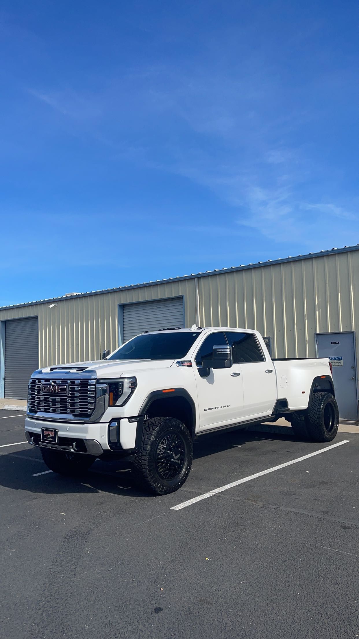 A white truck is parked in a parking lot in front of a building.
