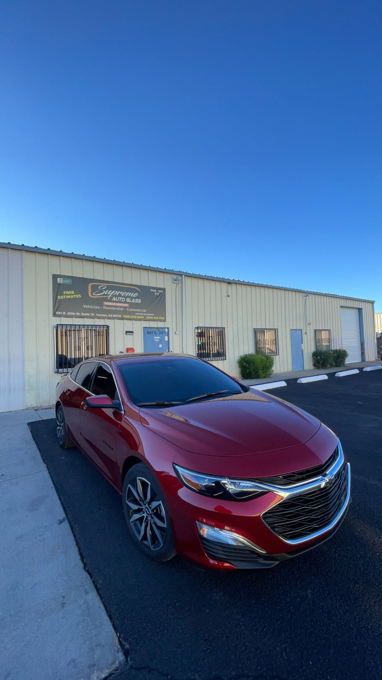 A red car is parked in front of a building.