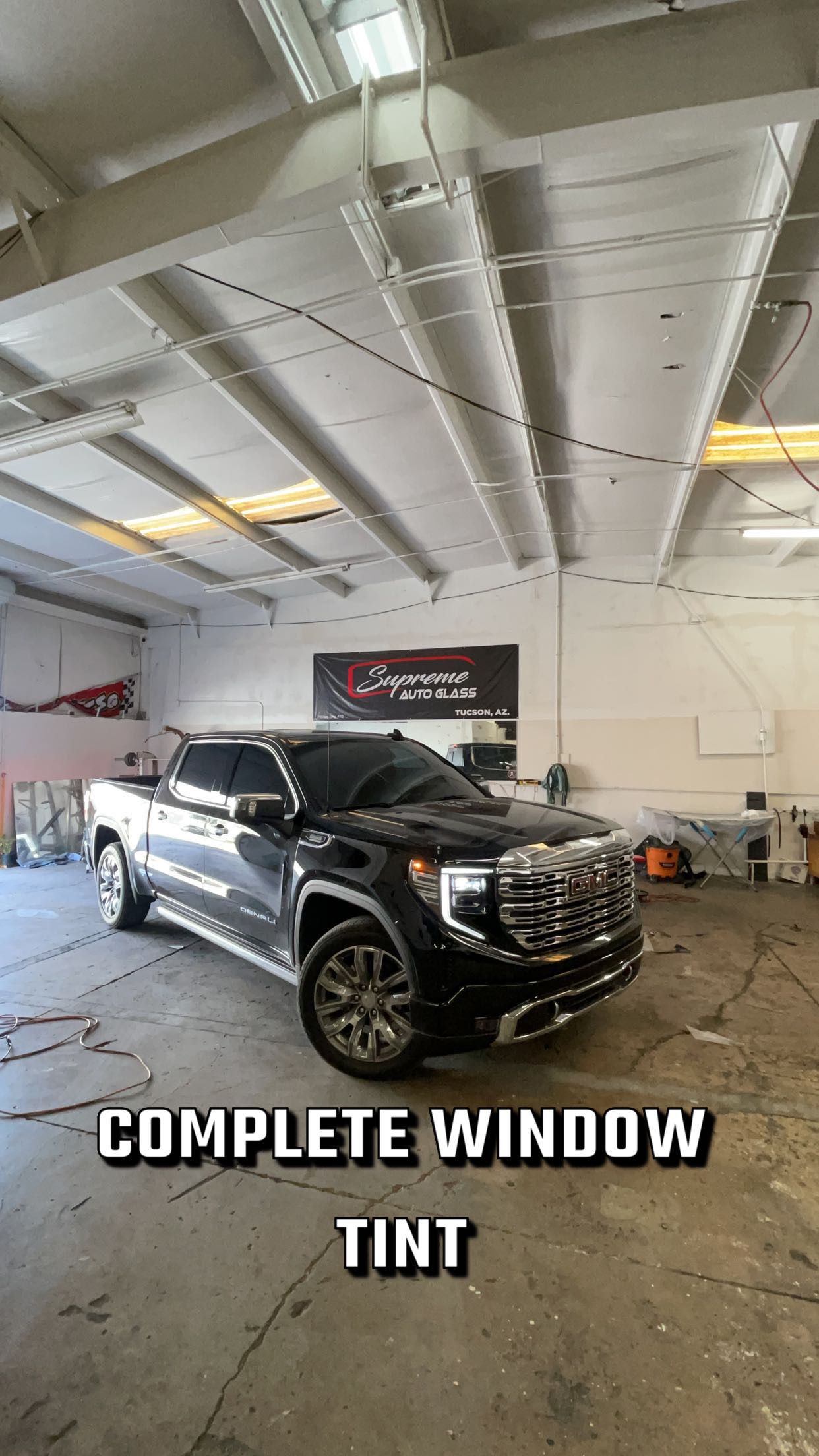 A black truck is parked in a garage with a complete window tint.