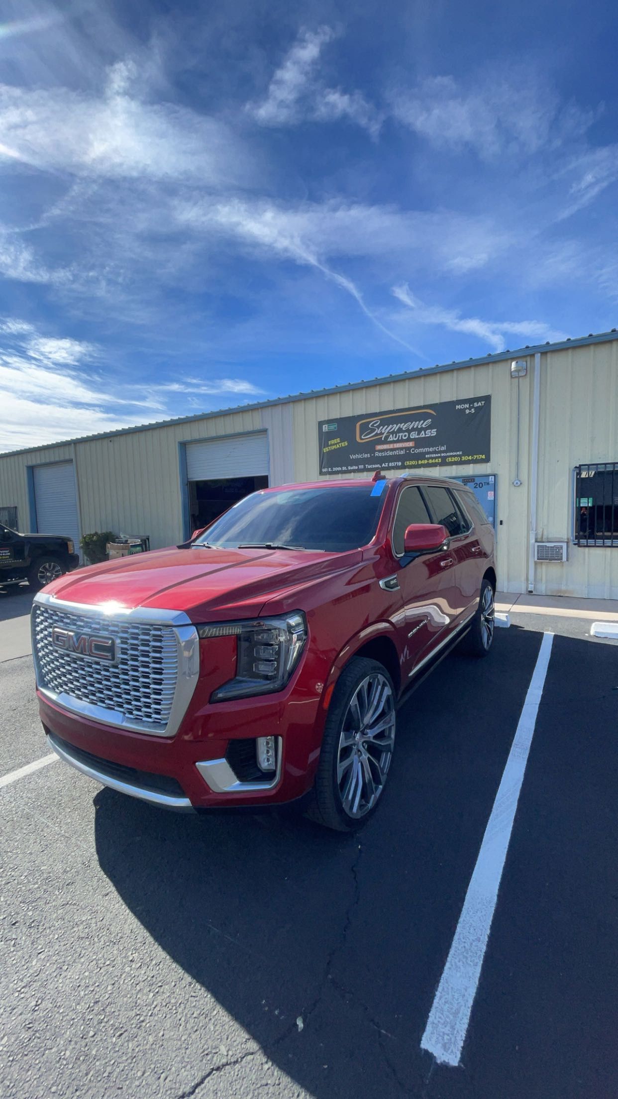 A red gmc yukon is parked in a parking lot in front of a building.
