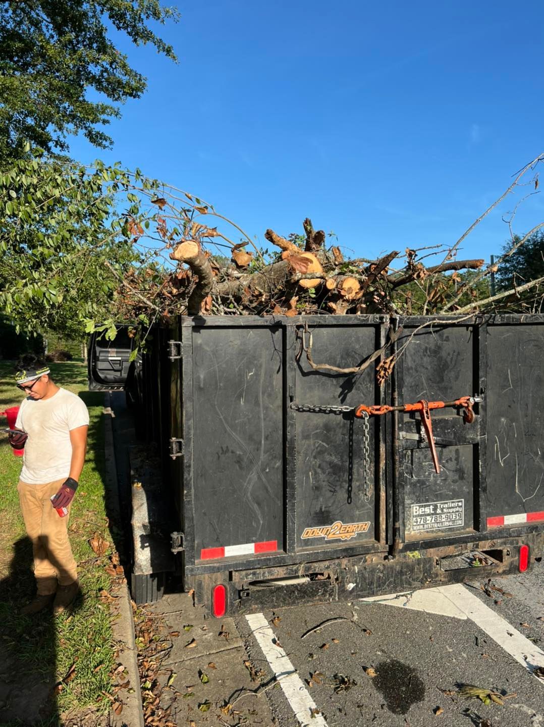 A man standing next to a dumpster full of logs