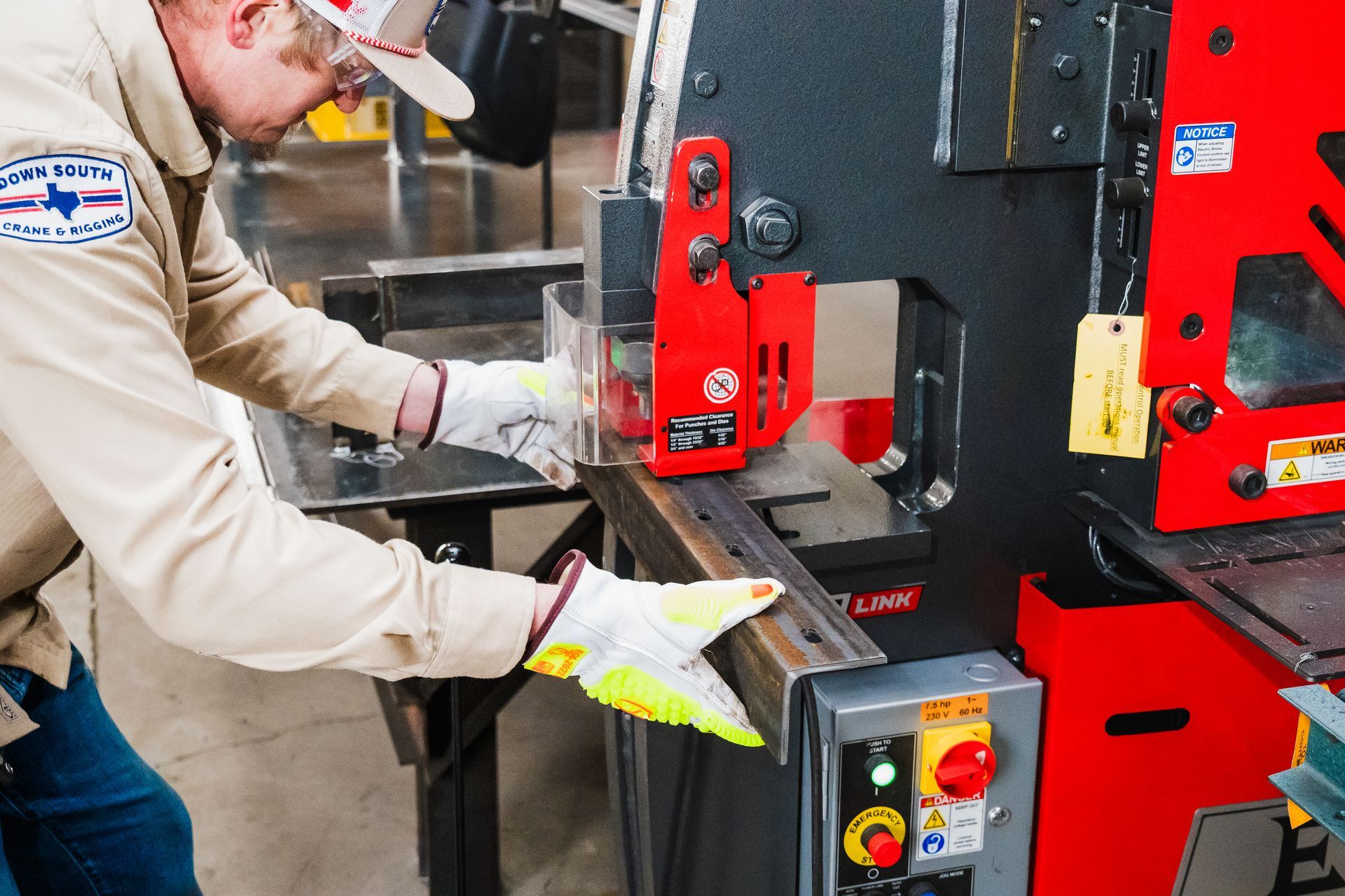 Person operating a red metal cutting machine, wearing safety gloves.