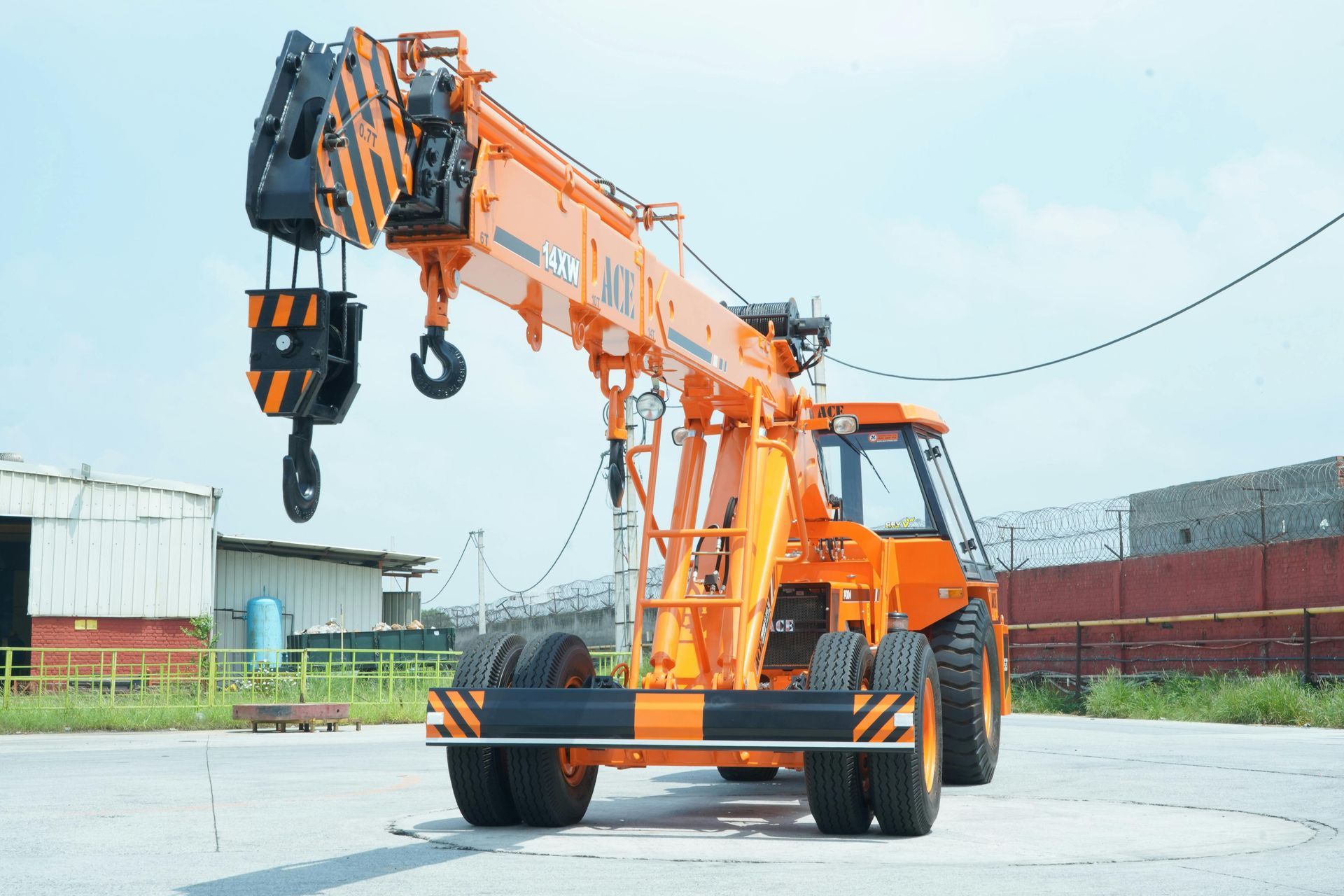 An orange industrial pick-and-carry crane parked on a paved lot under a clear sky.
