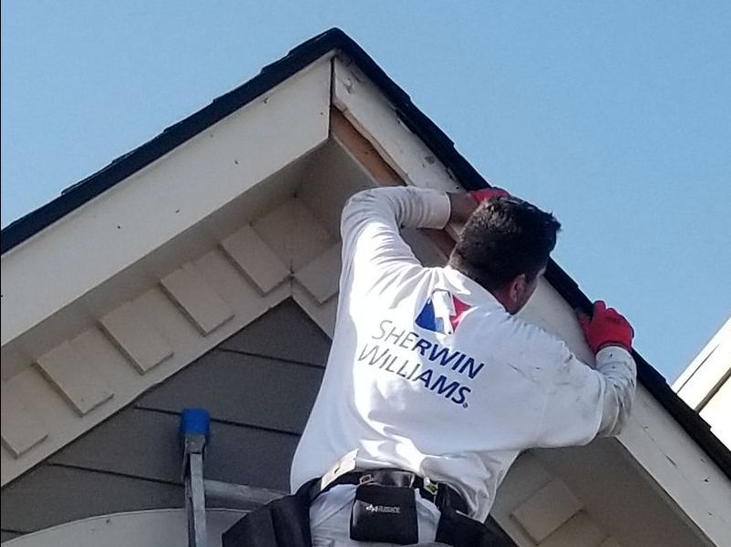 carpenter replacing fascia board on house