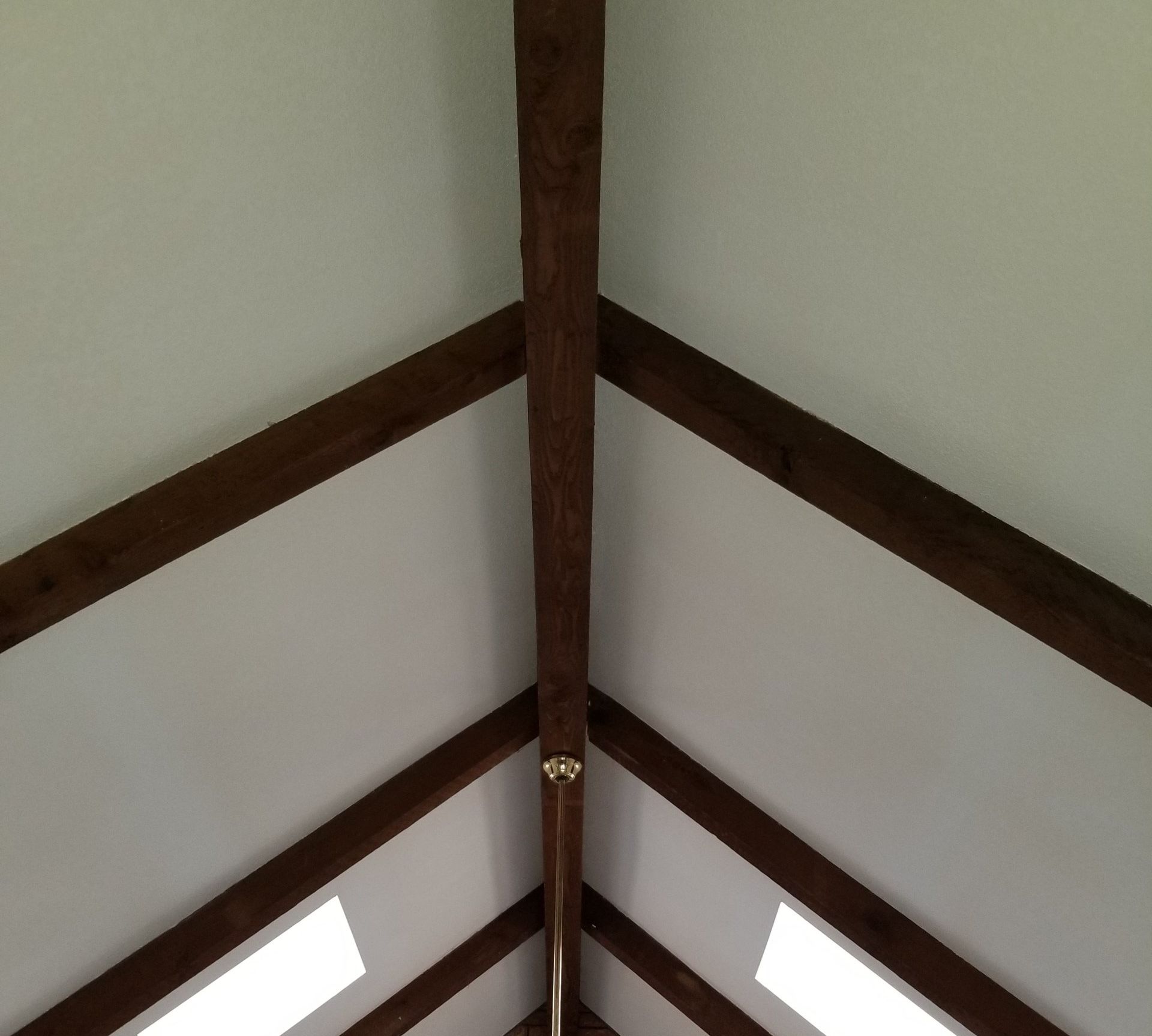 A vaulted ceiling, freshly painted white with dark wooden beams