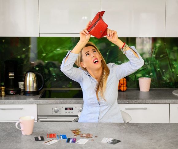 woman shaking out wallet looking for more money in the kitchen table don't pay too much home pros painting