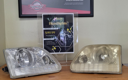Two car headlights displayed on a table, one silver and one gold, with a poster behind them | Dean's Tire & Auto