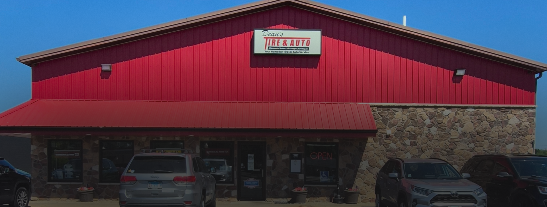 Red metal-roofed building with stone facade | Dean's Tire & Auto