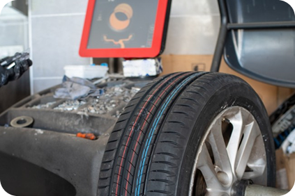 Car tire in front of a dusty workbench with a small red-framed screen and chair in a garage | Dean's Tire & Auto