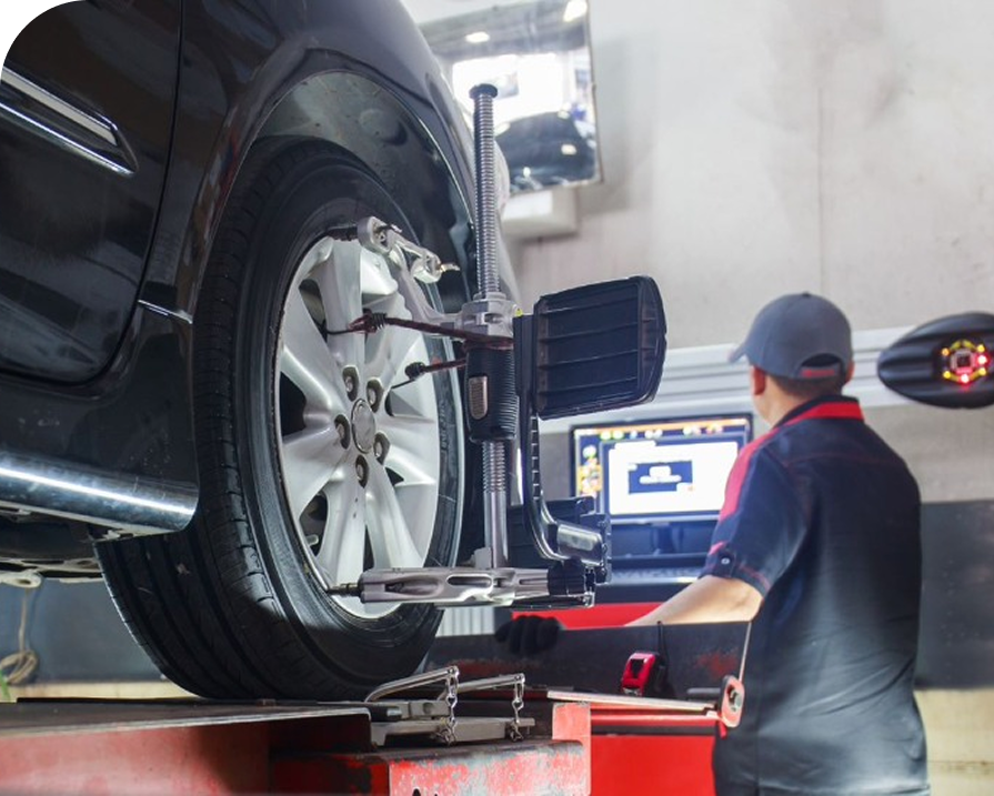 Car on alignment lift in auto shop while a mechanic works at a computer monitor | Dean's Tire & Auto