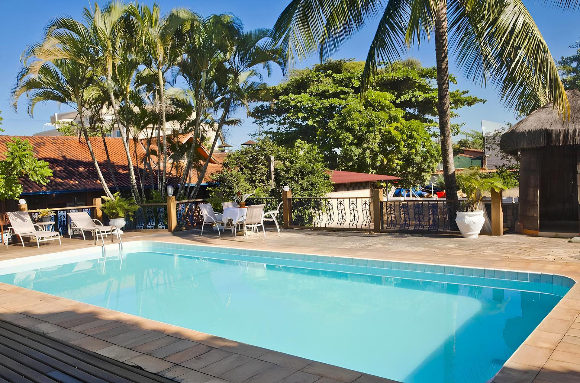 Uma grande piscina rodeada de palmeiras e cadeiras