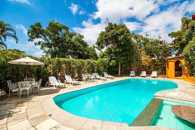 Uma grande piscina cercada por cadeiras e mesas em um dia ensolarado.