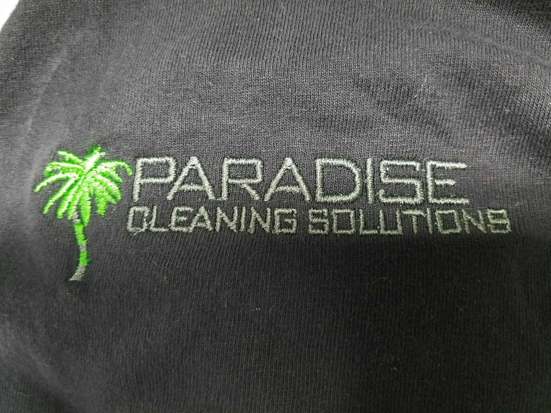 An embroidered green palm tree logo next to the text 