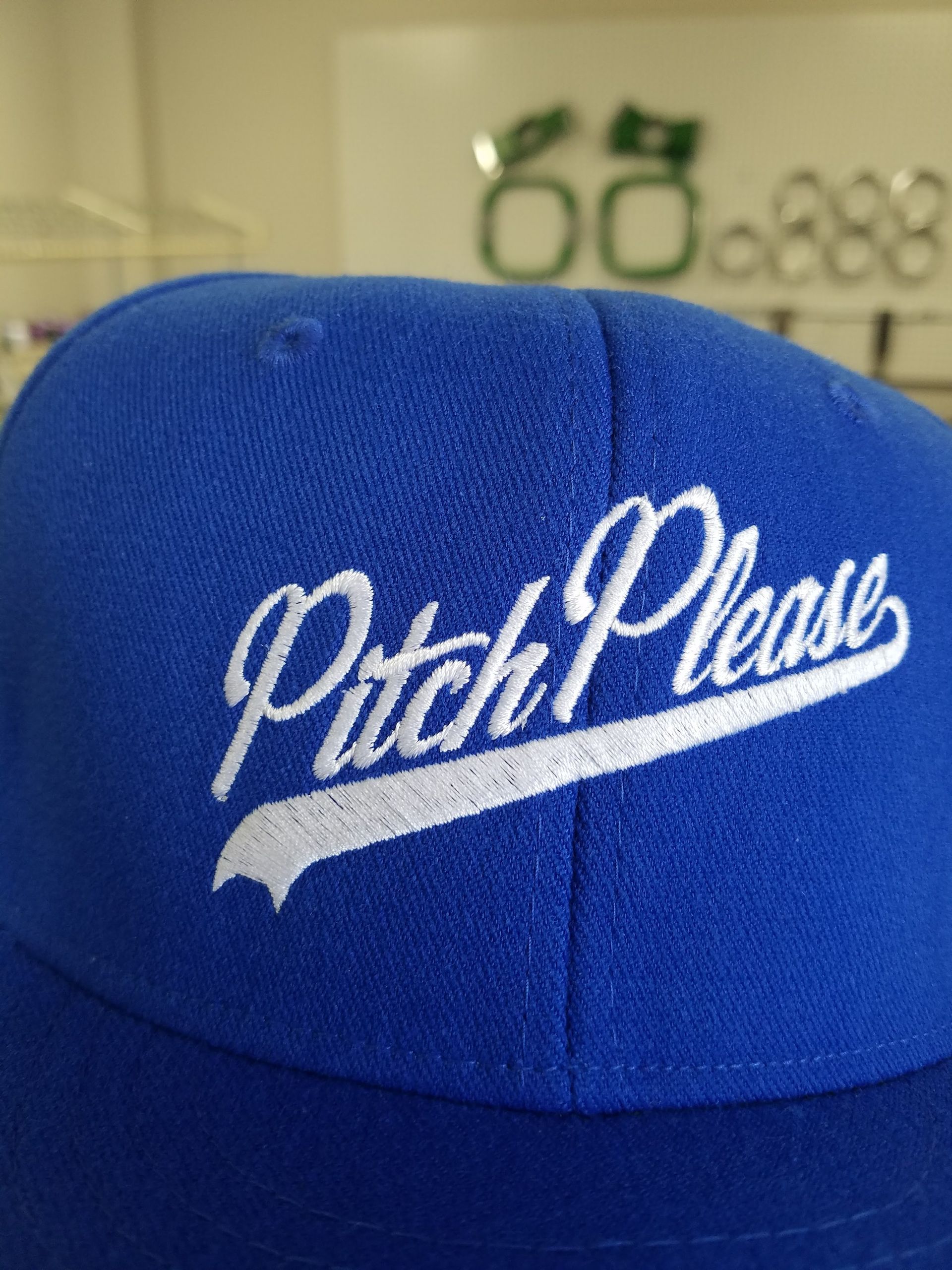 A bright blue baseball cap featuring white, cursive embroidered text that reads 