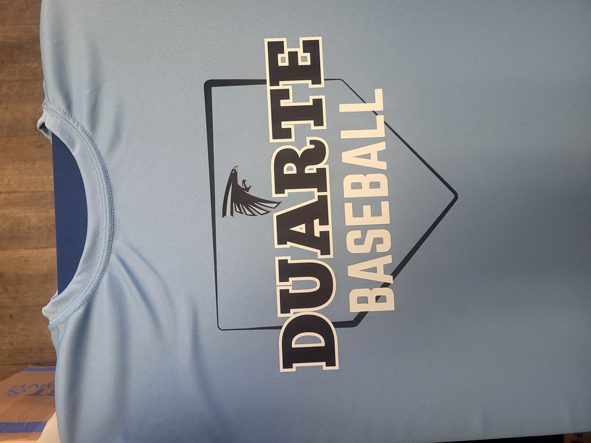 A light blue T-shirt featuring a home plate graphic with the text 