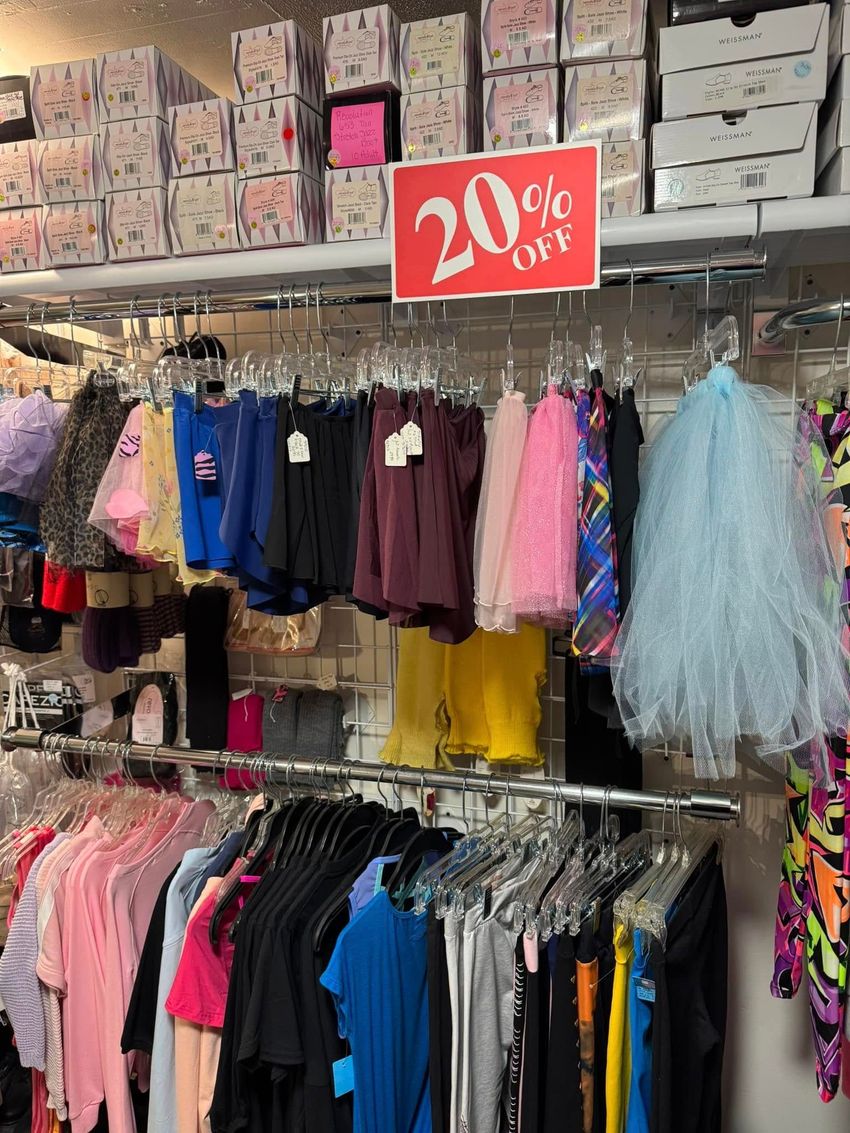 Clothing store with racks of apparel, including skirts. A sign indicates