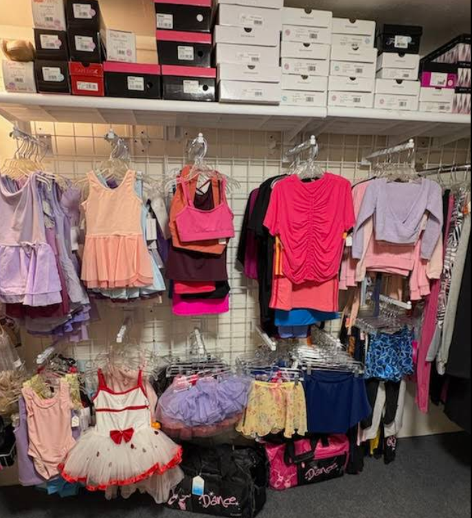Dancewear shop display with racks of leotards, tutus, and shoes on shelves.