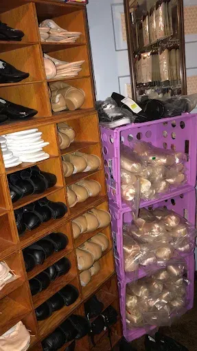 Wooden shoe shelves and stacked purple crates holding ballet shoes.