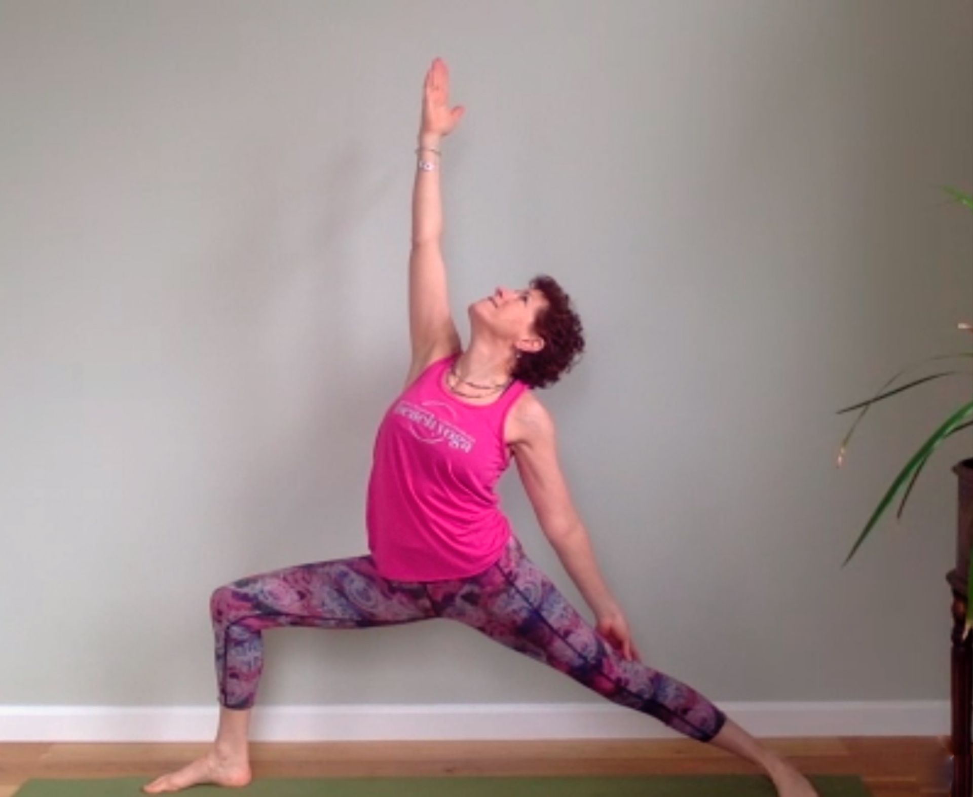A woman in a pink tank top is doing a yoga pose