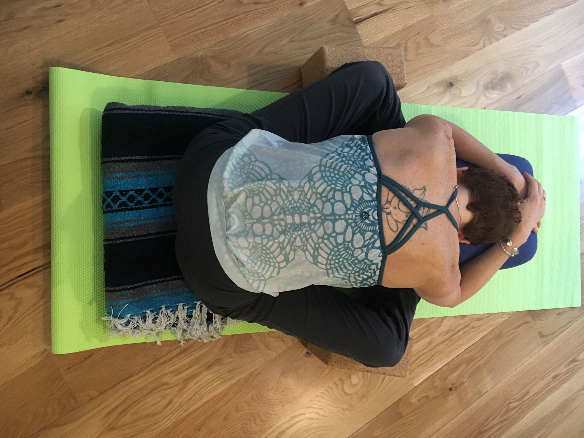 A woman is laying on a green yoga mat